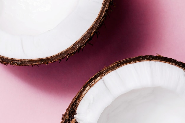 Half of a coconut lies on pink background