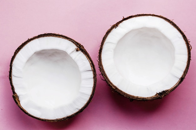 Half of a coconut lies on pink background