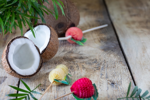 Half a coconut and a palm branch lie on a wooden table. Copy space