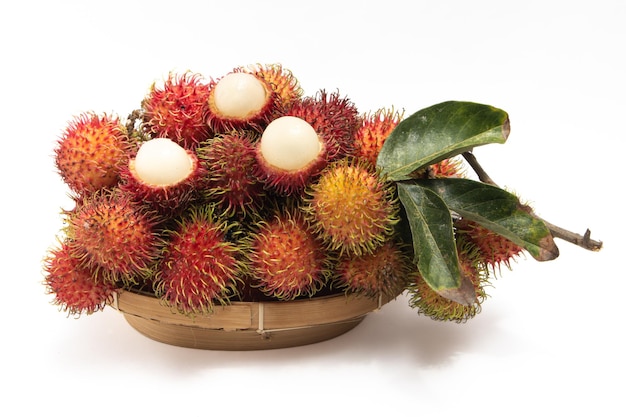 Half cut and a bunch of fresh rambutan fruit in a bamboo basket plate isolated on white background