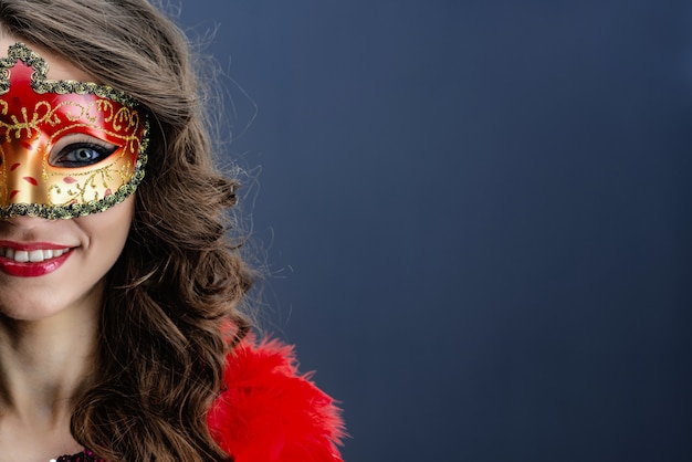 Half face of smiling woman wearing carnival mask over blue background