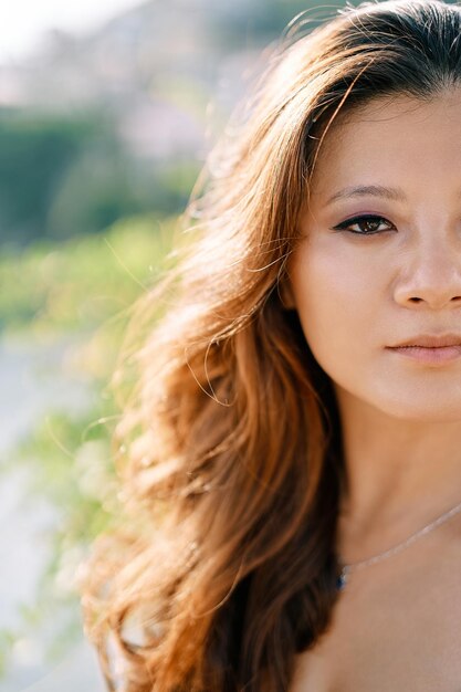 Half face of a young woman in a sunny garden