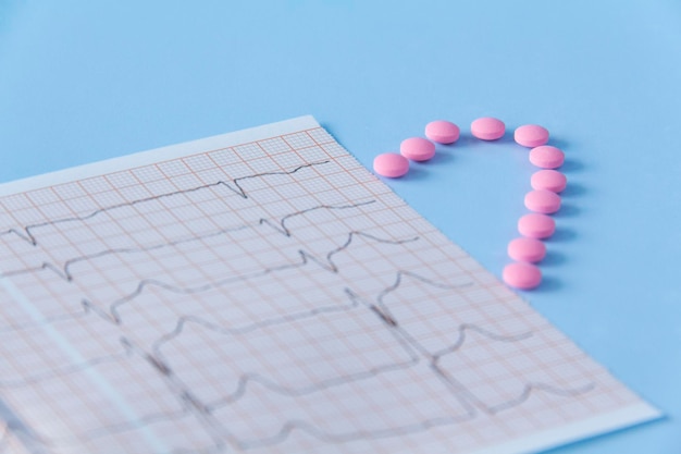 Half of a heart made of pink drugs and an electrocardiogram of the heart on a blue background The concept of a healthy lifestyle and timely medical examination