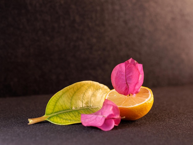 Half lemon with pink flowers on black background