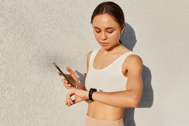 Photo half length portrait of athletic female connecting smartphone with fitness bend before training outdoor or running