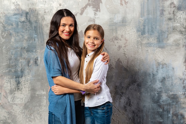 A half-length portrait of mother and daughter hugging each other