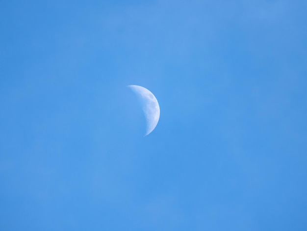 Half moon during daylight Moon is in the blue sky