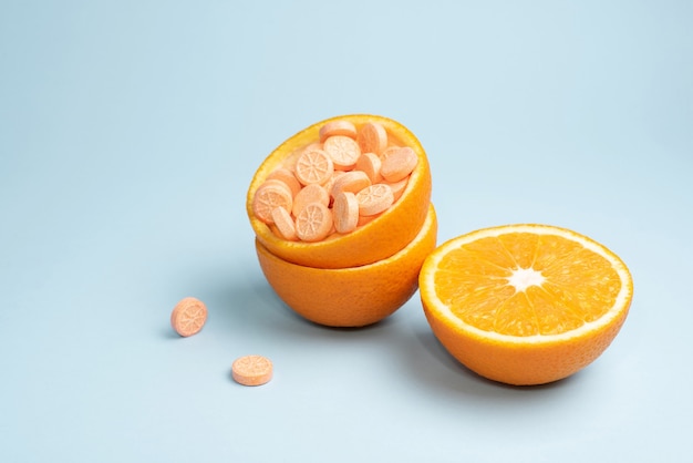 Half orange and peel with vitamin C tablets on a blue