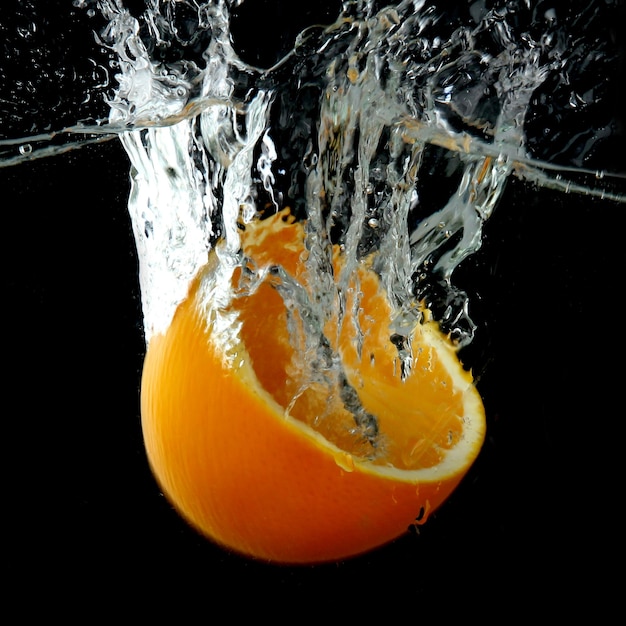 half of orange in the water on black background