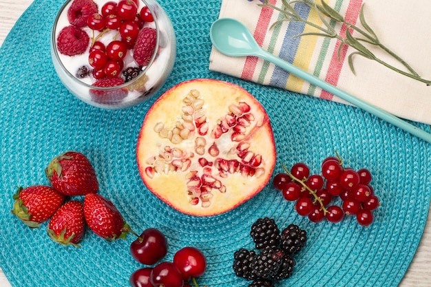 Half pomegranate and berries on a blue pad in a top view