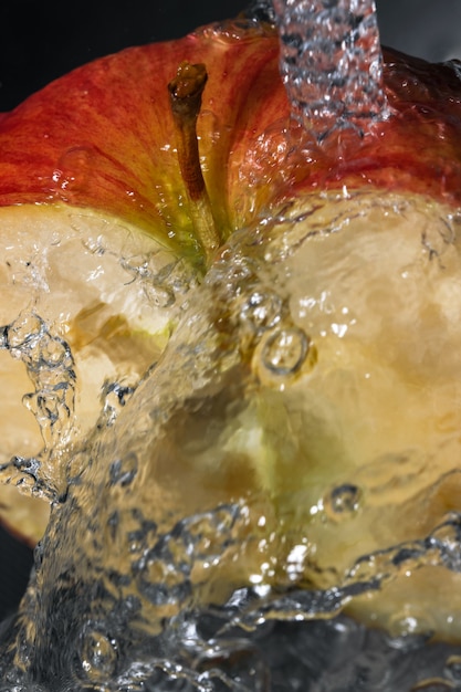 Photo half of a red ripe sweet apple under a stream of clean water close-up macro photography