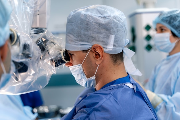 Half side view on neurosurgery doctor. Portrait of neurosurgeon. Equipment and medical devices in modern operating room. Operating theatre. Selective focus.