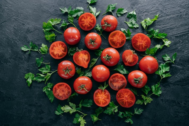 Half tomatoes and green parsley around on dark background Fresh ingredients for making vegetarian salad Harvested garden vegetables