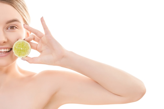 The half of the young woman face with a lime on the white background