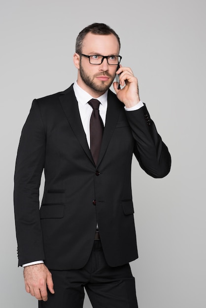 Halflength shot of young businessman in a suit talking on the phone with concerned look on his