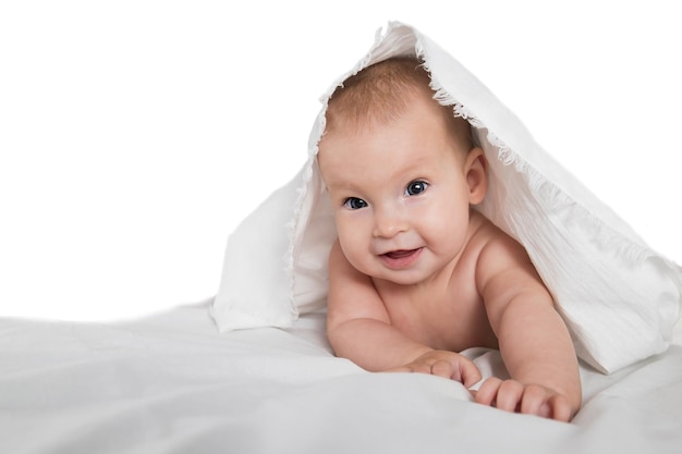 A halfyearold cute baby in a diaper and a towel lies on his stomach and looks cheerfully at the camera