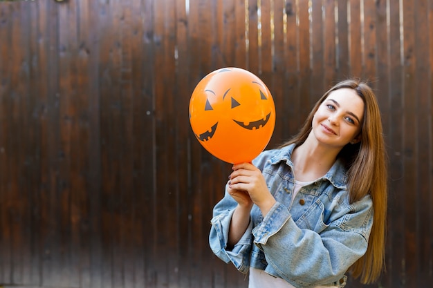 Halloween autumn background with girl holding orange air ballon