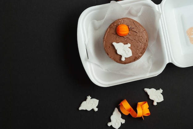 A halloween cake with a white frosting and a pumpkin on top.