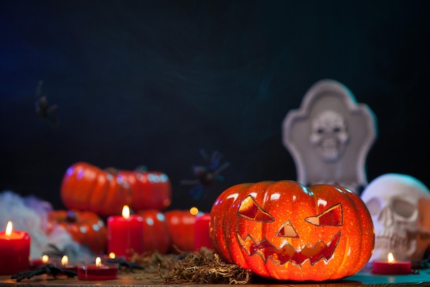 Halloween candles lighting a creepy carved orange pumpkin. Halloween decorations on wooden table.