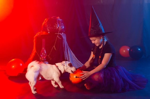 Halloween and celebration concept child girl in witch costume with halloween pumpkin playing with do