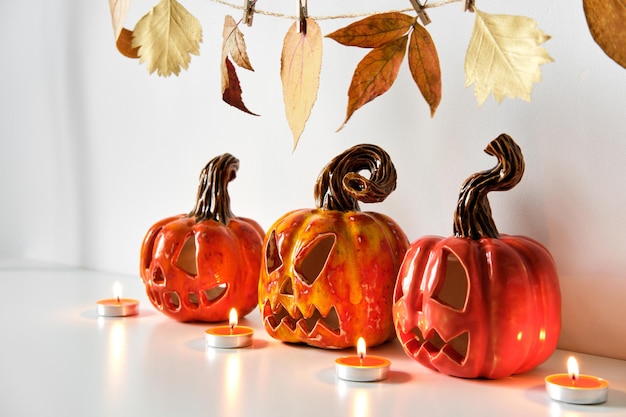 Halloween composition with ceramic pumpkins jack lantern and candles on table wall background Home decoration