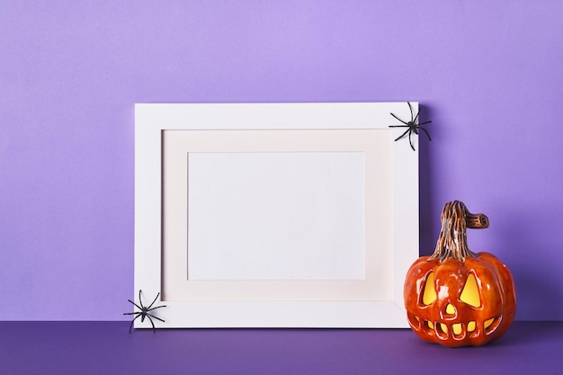 Halloween composition with ceramic pumpkins jack lantern and frame on table wall background Greeting card template