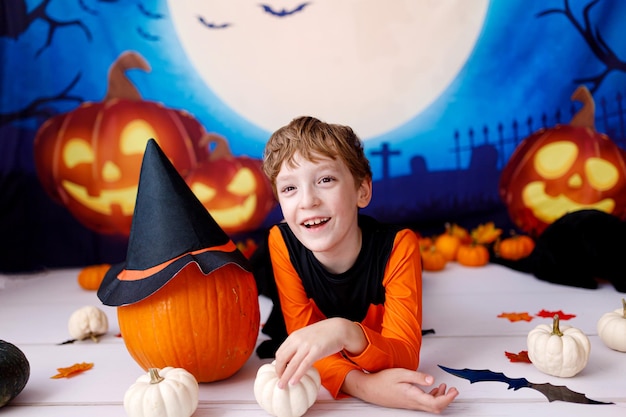 Halloween concept. Smiling kid with pumpkins on halloween spooky background.