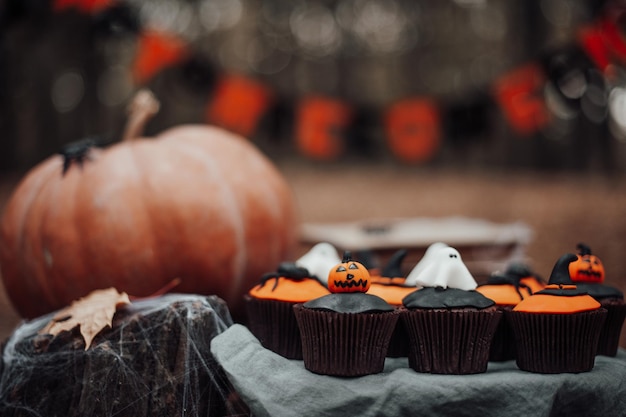 Halloween cupcakes and holiday decor at maple leaves among trees in autumn season outdoor