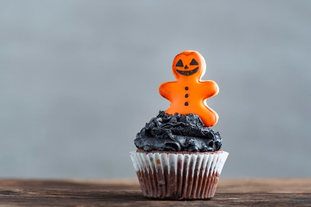 Halloween cupcakes with gingerbread man on wooden table on grey background Delicious halloween party muffins