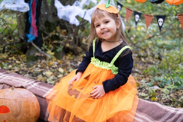 Halloween. cute girl in pumpkin costume with pumpkin outdoor, having fun, celebrating Halloween