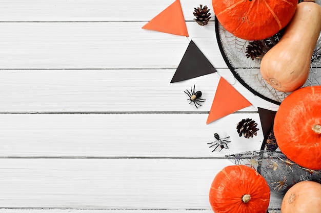 Photo halloween day pumpkins and halloween paraphernalia witchs hatspiders are lying on white table