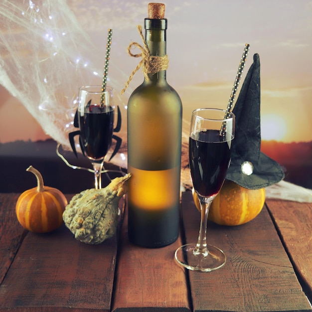 Halloween decorations, in glasses a cocktail of red wine, illumination, landscape with a sunset