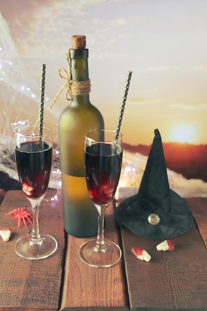 Halloween decorations, in glasses a cocktail of red wine, illumination, landscape with a sunset