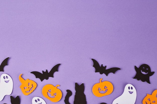 Halloween decorations pumpkins on violet background Halloween party greeting card Copy space Flat lay top view overhead