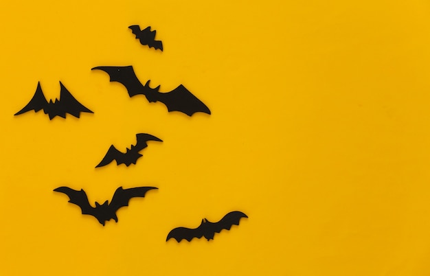 Halloween, decorations and scary concept. Black bats fly over yellow