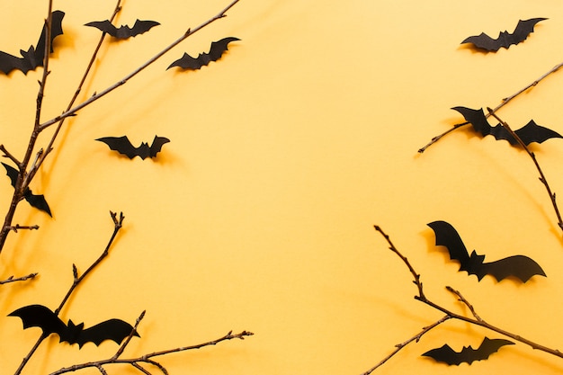 Halloween decorations with bats and branches on orange background halloween concept flat lay top