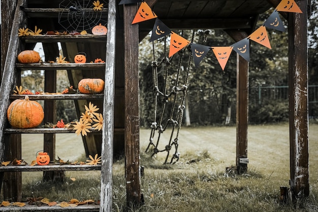 Halloween design courtyard with dry fall leaves Beautiful wooden porch of the house with pumpkins in autumn time