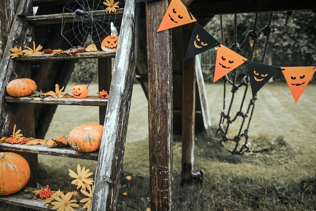 Halloween design courtyard with dry fall leaves Beautiful wooden porch of the house with pumpkins in autumn time