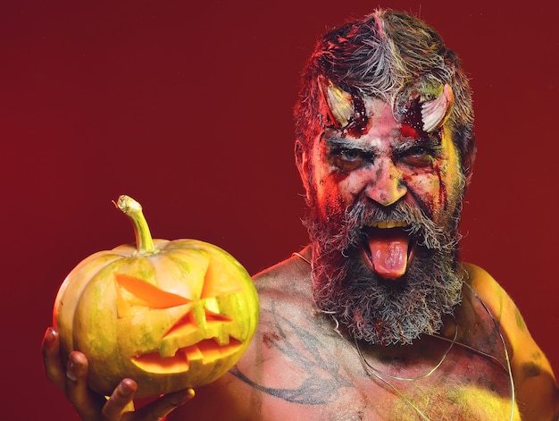 Halloween devil with bloody horns show tongue on red background