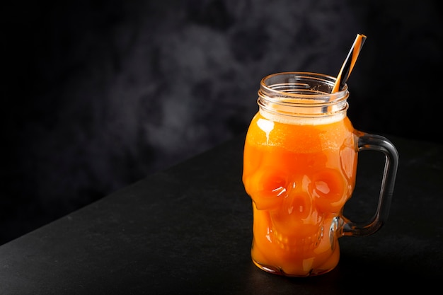 Halloween drink. Pumpkin drink in skull glass.