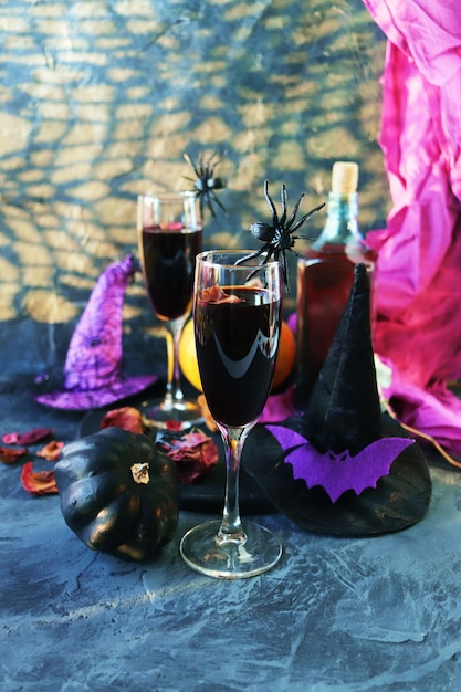 Halloween drinks wine pumpkins mystical decorations dry roses and shadows on a black background