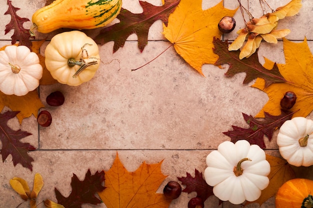 Halloween festive autumn background Autumn decor from pumpkins berries maple leaves and chestnuts on old rustic stone tiles backgrounds Concept of Thanksgiving day Halloween Top view copy space