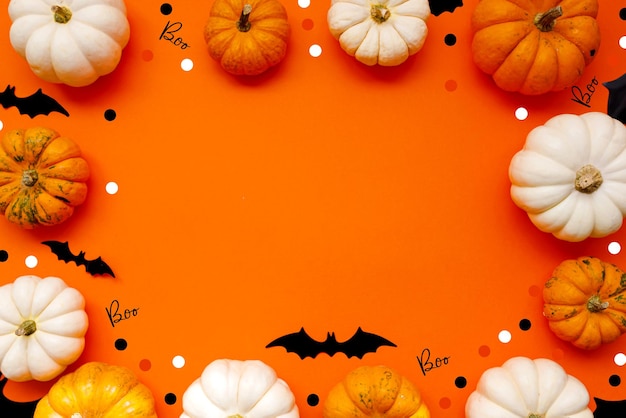 Halloween flat lay composition of black paper bats fand pumpkins on orange background Halloween concept