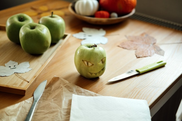 Halloween fruit ideas halloween green apple with creepy carved face on wooden table at home healthy