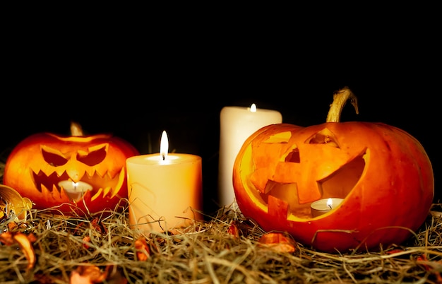 Halloween glowing pumpkins and candles on a table with a straw