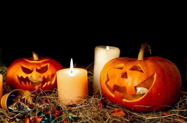 Halloween glowing pumpkins and candles on a table with a straw