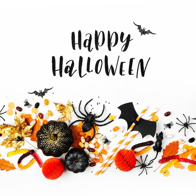 Halloween holiday background with colorful candy, bats, spiders, pumpkins and decorations. Flat lay. View from above