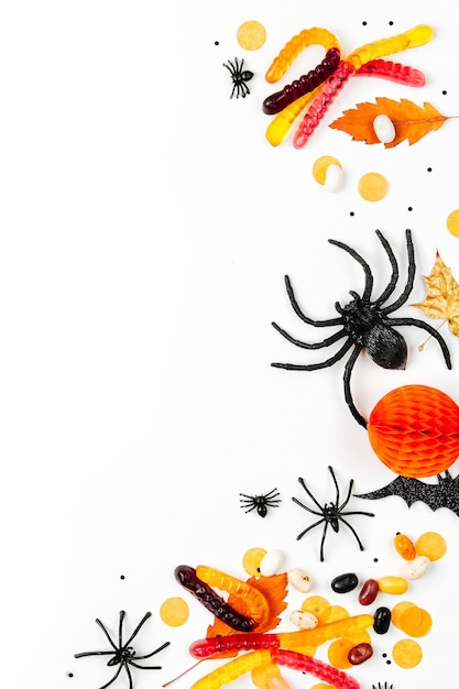 Halloween holiday background with colorful candy, bats, spiders, pumpkins and decorations. Flat lay. View from above