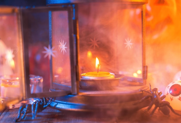 Halloween holiday concept design of pumpkin candle spooky decorations with blue tone smoke around on a dark wooden table close up shot