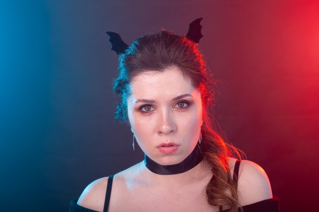 Halloween, holidays and carnival concept - vamp woman in collar and bat's ears in gothic style